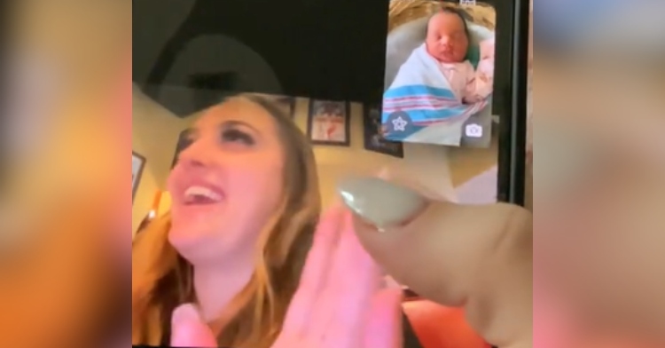 View of a FaceTime call. The caller, Ashley Nicole, is showing off her baby. Meanwhile, the person Ashley's calling, her sister, has her hand thrown up and is looking away laughing, mouth agape from shock.