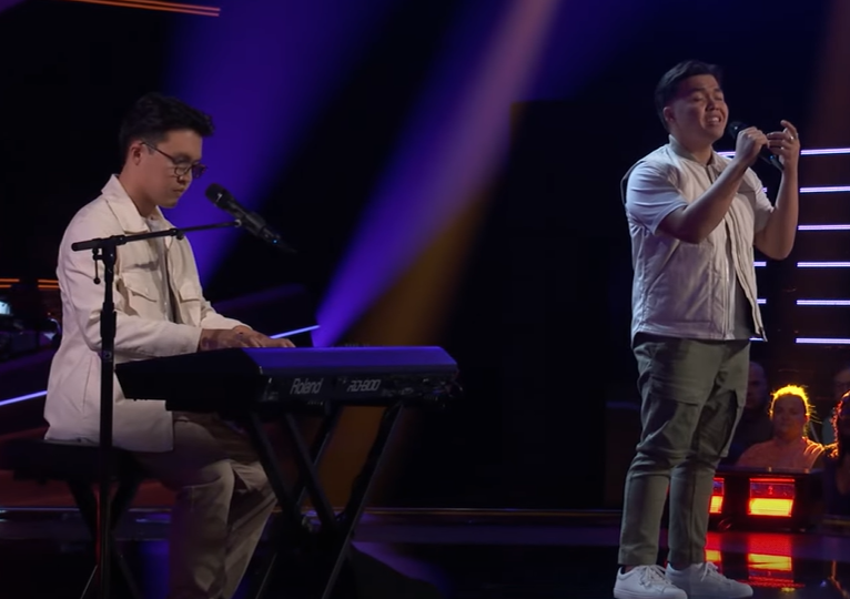 The Garcia twins sing on "The Voice" stage with one of them standing and the other playing the piano.
