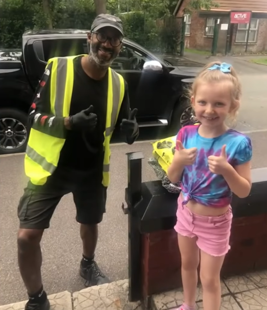 Delivery driver Tim Joseph and 8-year-old Tallulah McLellan both give two thumbs up as they smile outside.