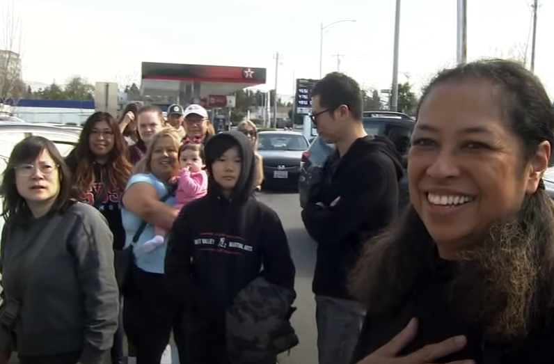 A woman smiles as a huge line forms outside her business.