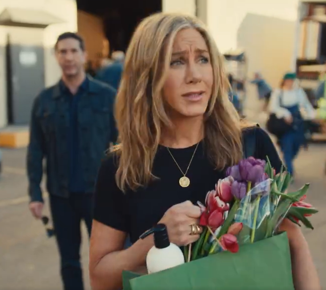 Screenshot of Jennifer Aniston and David Schwimmer in an Uber Eats Super Bowl commercial. Aniston looks annoyed as she carries an order and walks away from Schwimmer who is standing behind her at a distance.