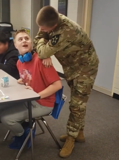 A man in a military uniform sneaks up behind his surprised brother.