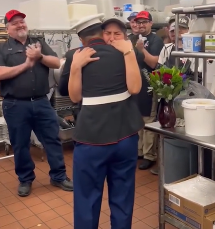 A mom hugs her Marine daughter while others applaud.