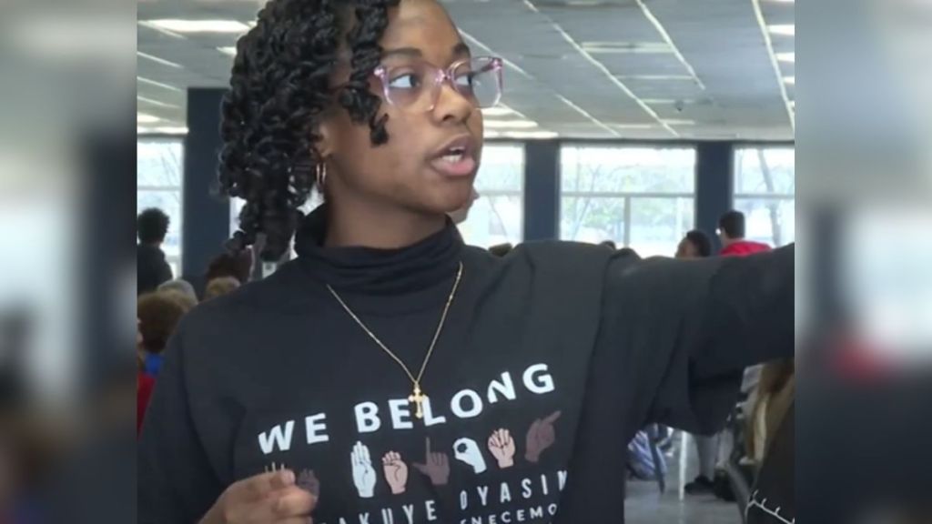 A high school student wears a shirt that says "We Belong."