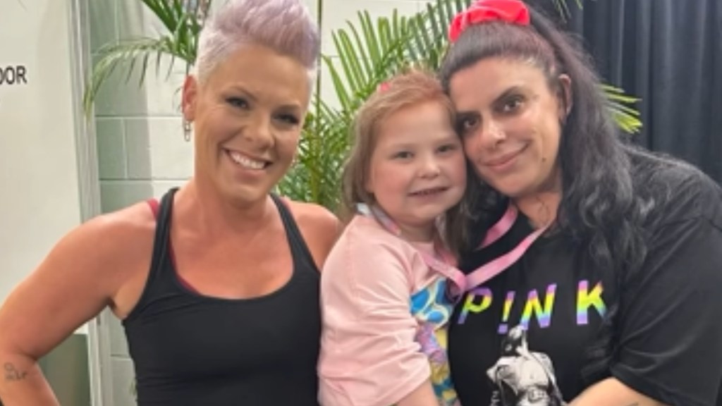 Pink, Lillian, and Angela smile for a photo together. Lillian is in Angela's arms but she's next to Pink.