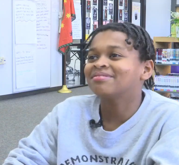 Dewayne Harris smiles as he sits in a classroom, talking to local news crew.