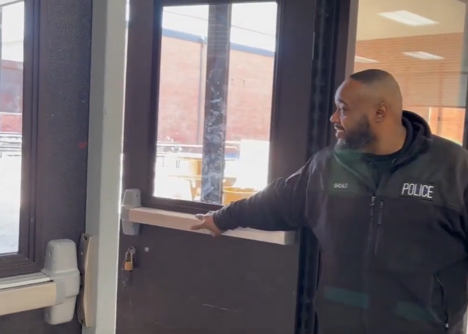 Lyndell Shoals smiles as he holds the front door open for students.