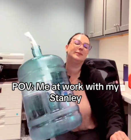 A woman carrying a water cooler like a bottle.