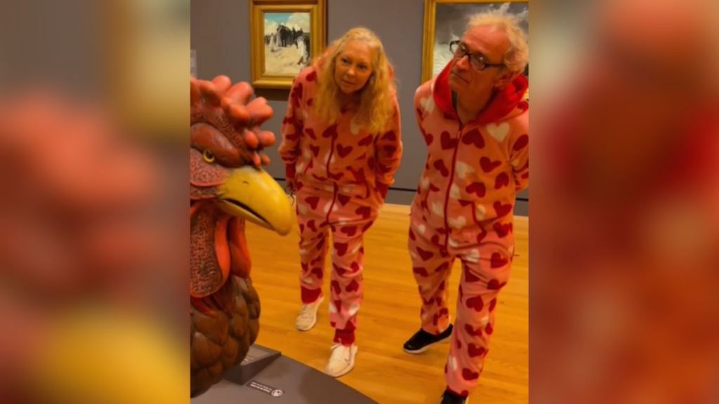 A Mom and Dad wearing matching pajama onesies in a museum.