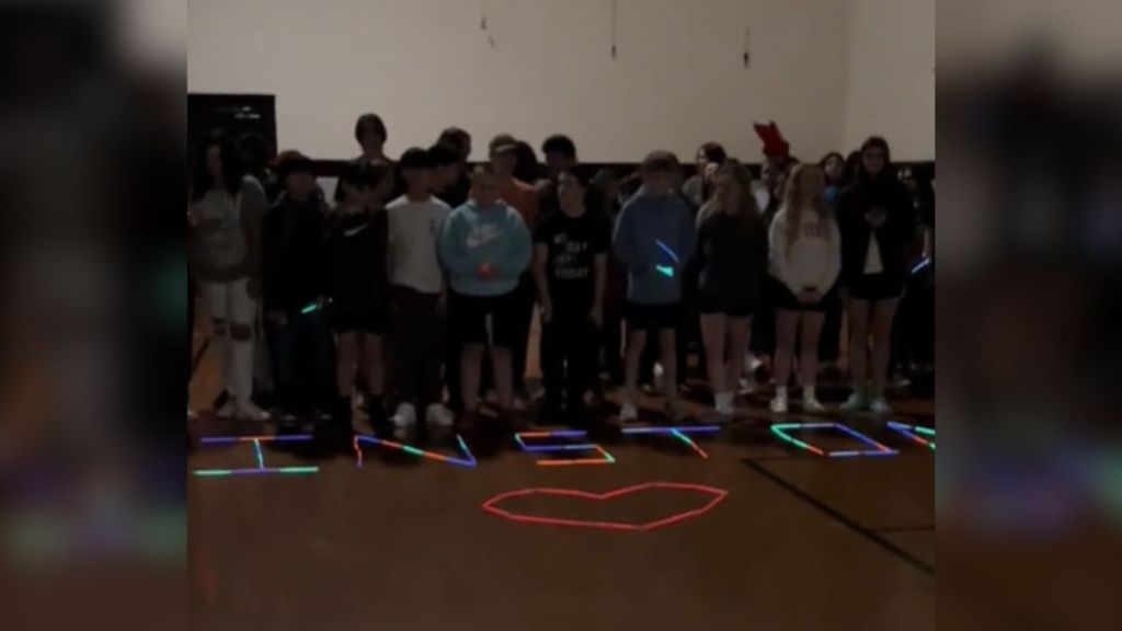 A group of middle school students surprise their teacher with a glowstick message.