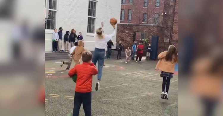 A teacher plays basketball with her students.
