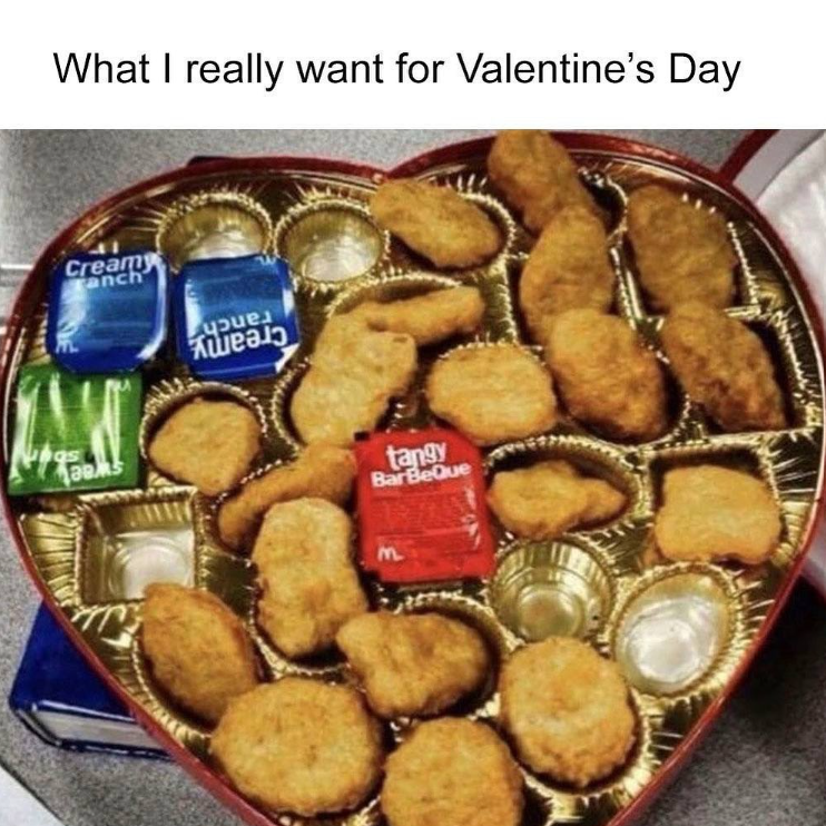A heart-shaped box with chicken nuggets and three different types of sauces. Text above the image reads: What I really want for Valentine's Day