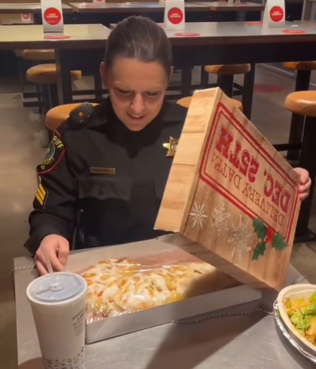 A police woman is surprised when she opens a pastry box in a restaurant.