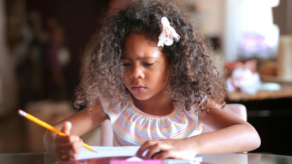 Stock image shows a girl concentrating on homework.