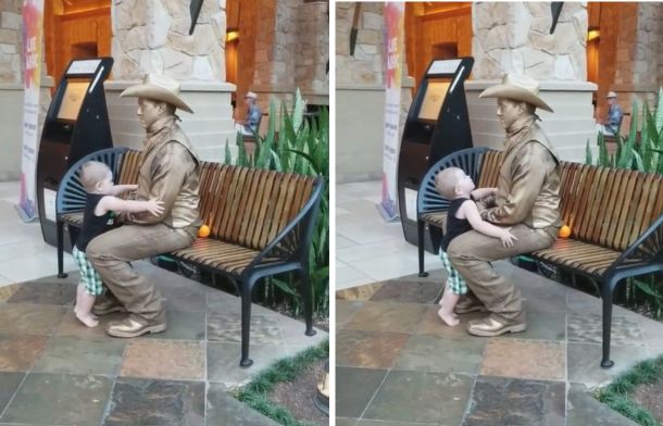 A young boy leans in for a hug, then senses something off. He pulls away and looks up at the statue man.