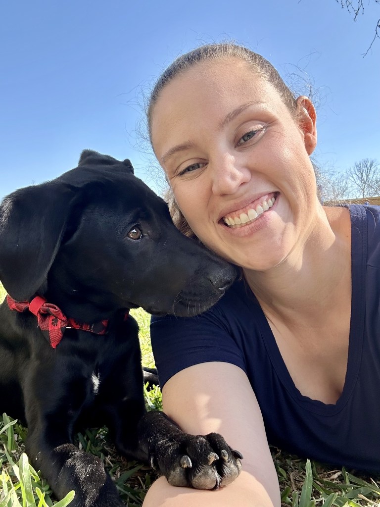 A woman with POTS smiling next to her new dog.