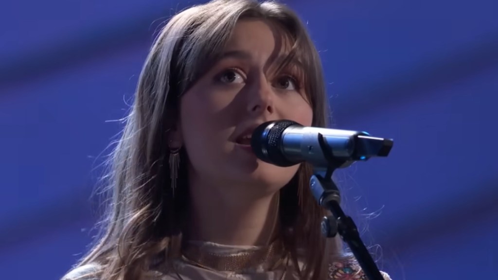 Close up of Anya True singing into a mic on "The Voice." She's looking up and out of the corner of her eyes.