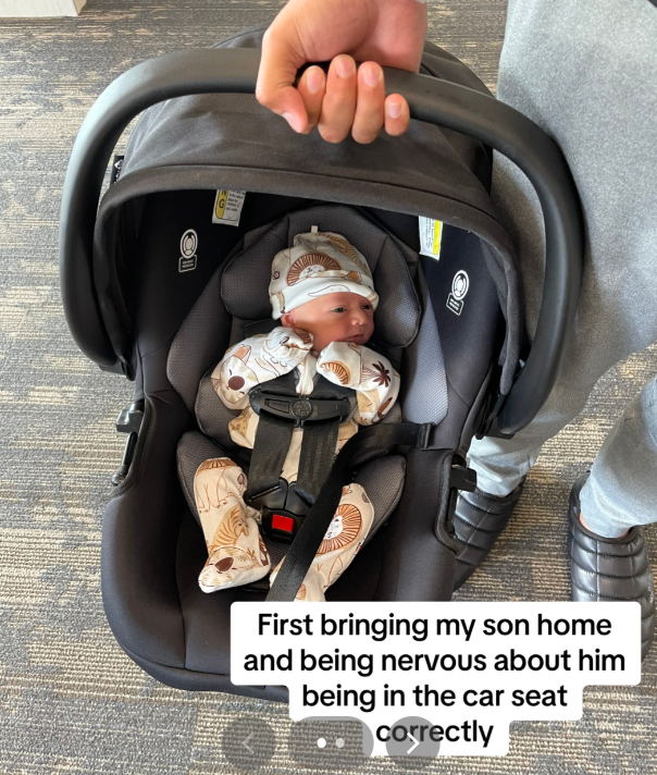 A parent carrying their baby in a car seat.