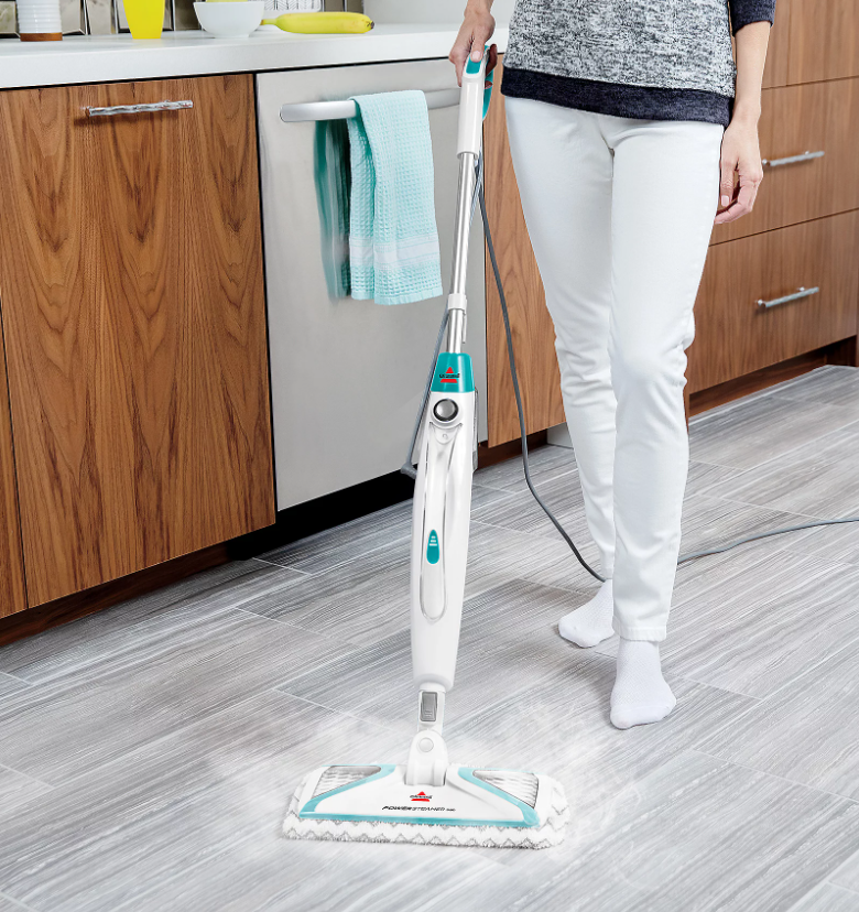 A woman spring cleaning in her kitchen with a steam mop.