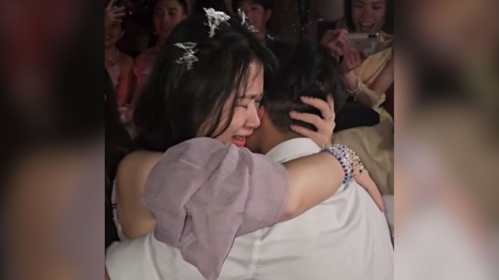 A couple in the audience at a concert embraces after their double proposal.