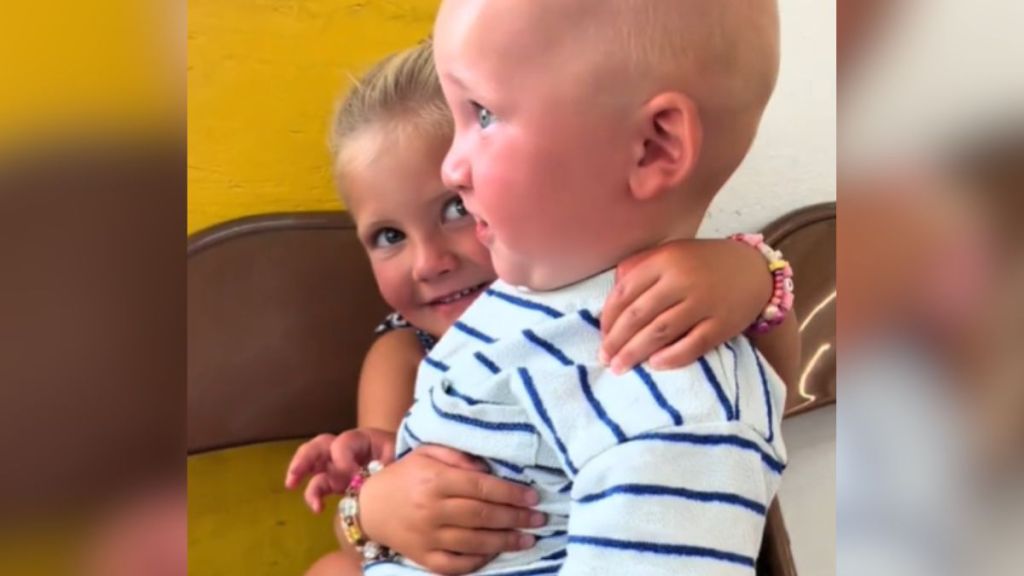 A little girl holds her baby brother, who is giant for his age.