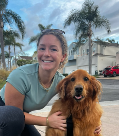 A woman hugging her golden retriever outdoors.
