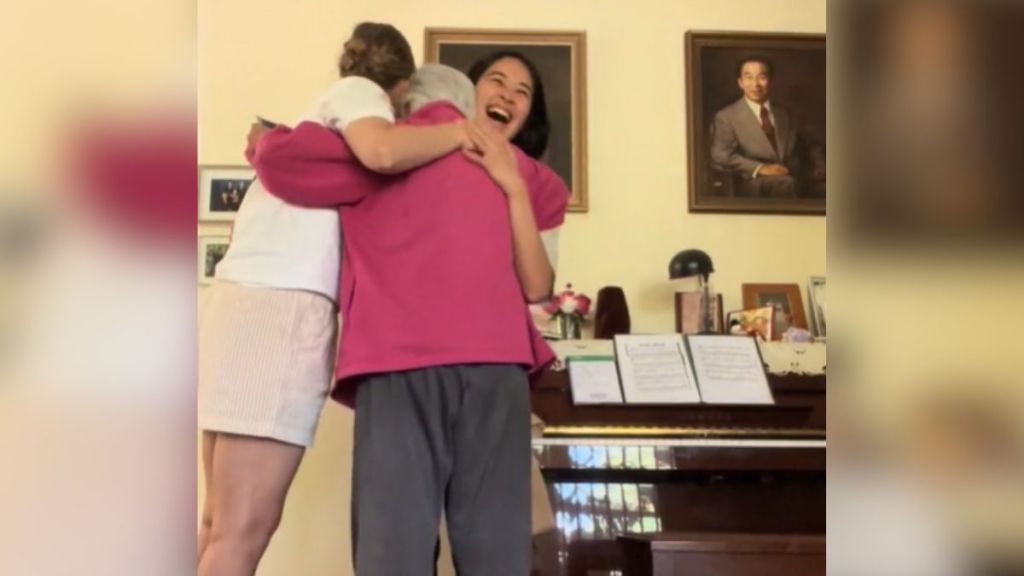 A grandma hugs her granddaughter and granddaughter-in-law after their pregnancy reveal.