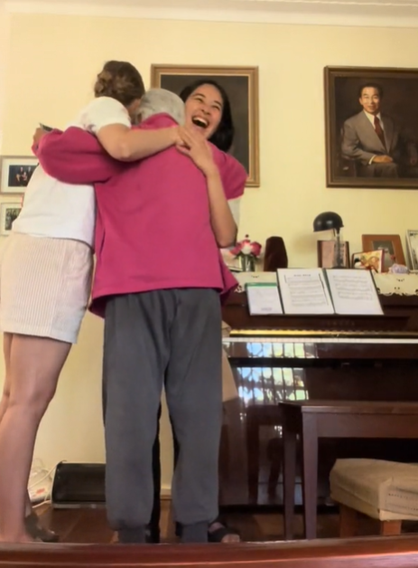 A grandma hugs her granddaughter and granddaughter-in-law after their pregnancy reveal.