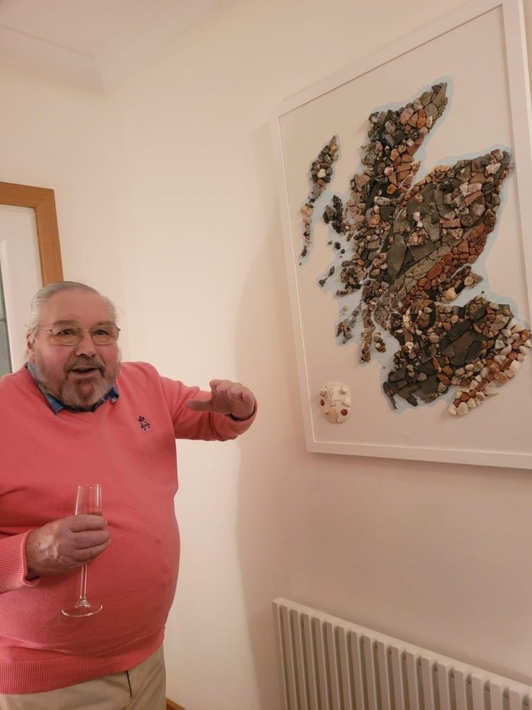 A grandpa shows off the map he made out of rocks. 