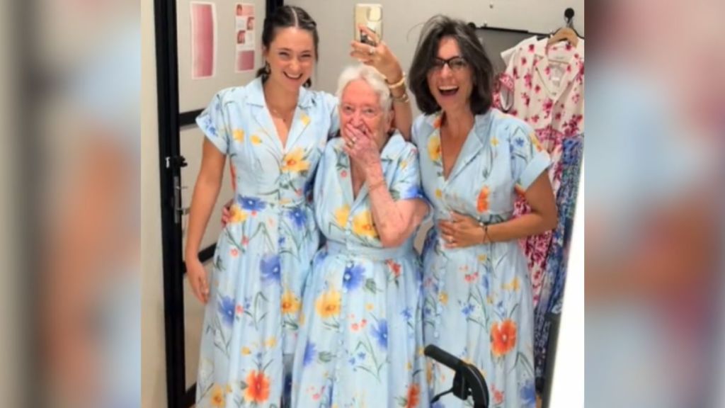 A great grandma and two younger women wearing matching dresses.