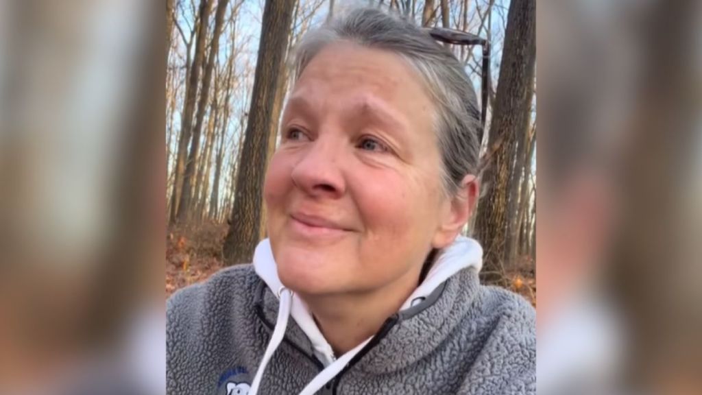A grieving woman in the woods smiles through her tears.