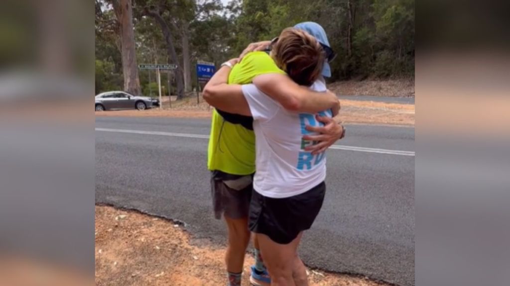 A runner hugs his mom by the roadside.
