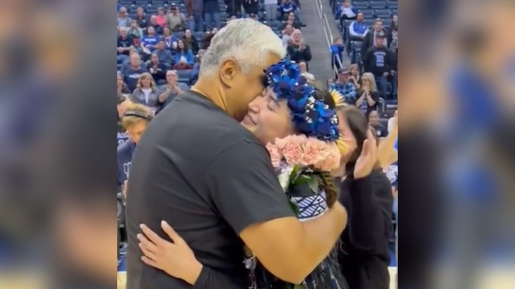 Close up of BYU basketball player Kaylee Smiler smiling as she hugs her dad on the court.