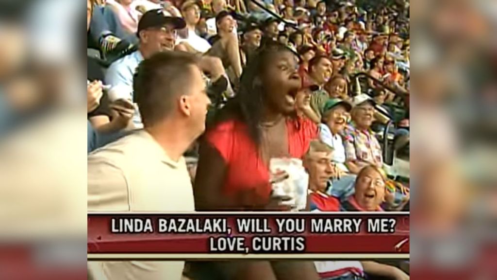 A woman is shocked when she sees her boyfriend's proposal on the kiss cam.