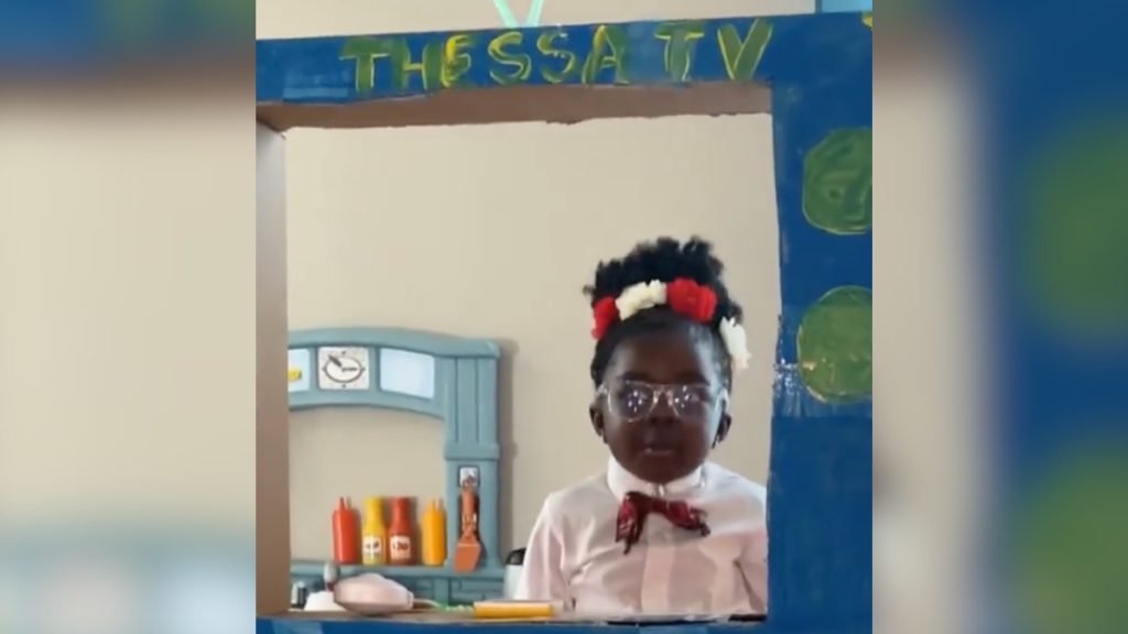 little girl playing news in cardboard box