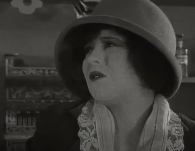 Close up of Clara Bow in a silent film. She's looking to the side at someone off screen. She looks upset.