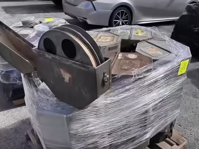 A stack of old film reels with one open on top. It's in a parking lot.