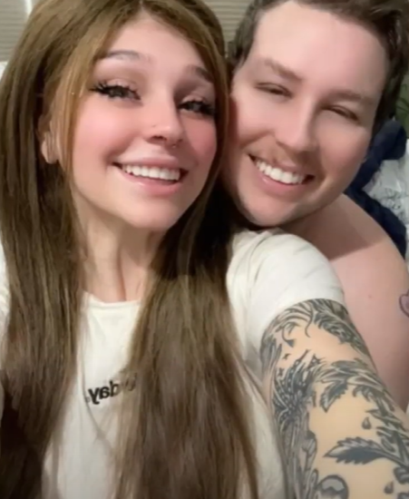 Hannah and Cody smile for a selfie. Hannah is wearing the wig made from his hair.