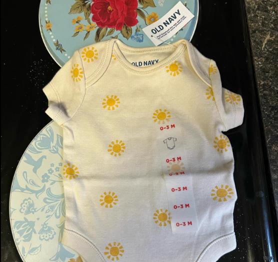 Top-down view of a onesie with little suns on them. The onesie is from Old Navy and is for a 0-3 month old.