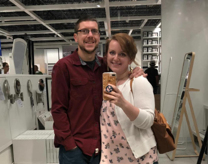 Jordan and her husband smile, arms around one another, as they take a photo in a mirror at a store.