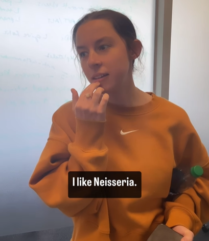 A woman in a yellow sweater says, "I like Neisseria."