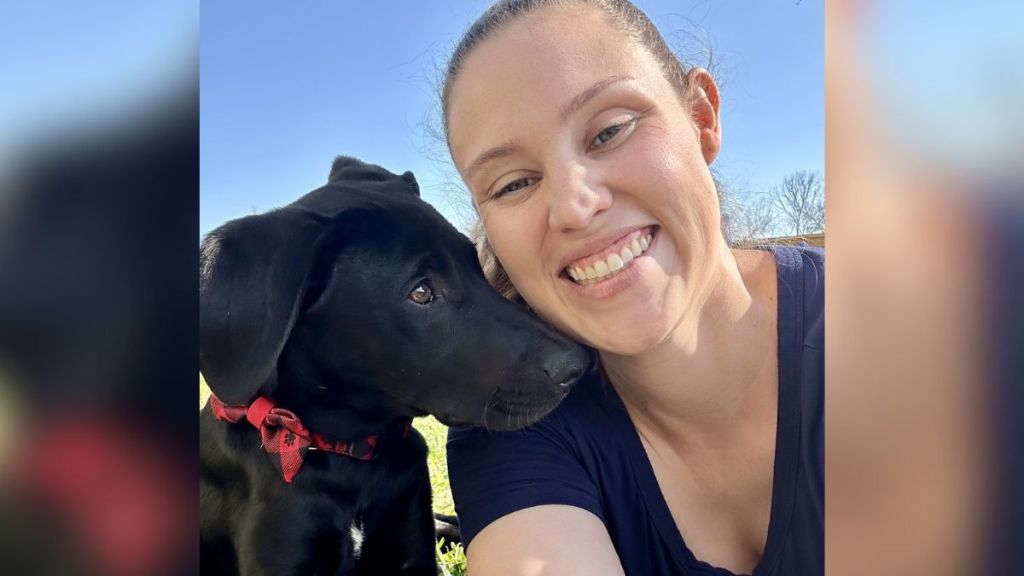 A woman with POTS smiling next to her new dog.