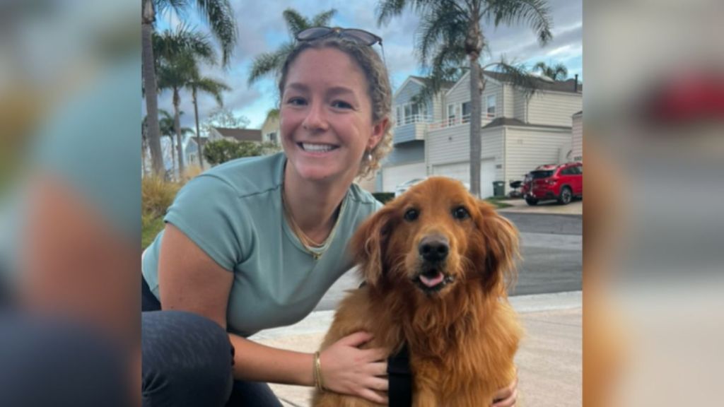 A woman hugging her golden retriever outdoors.