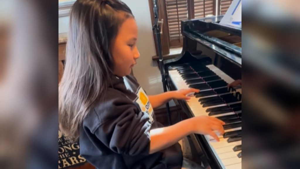 Side-view of a 7-year-old girl playing the piano.