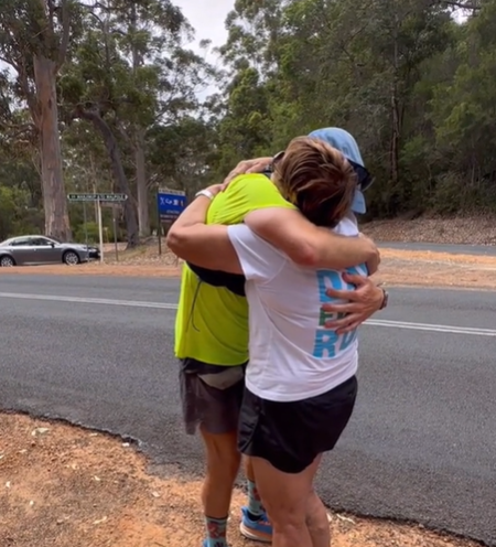 A runner hugs his mom by the roadside.
