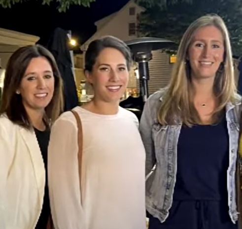 Three sisters standing together outside and smiling.