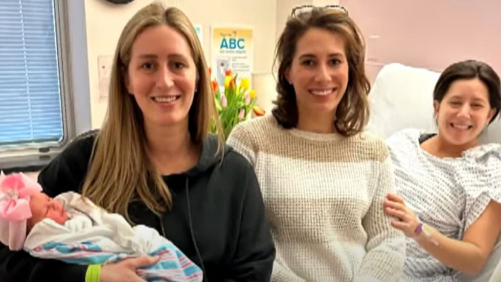 Three sisters in a hospital, one of them holding a baby.