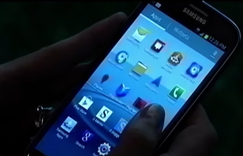 Close up of someone holding a cell phone in the dark.