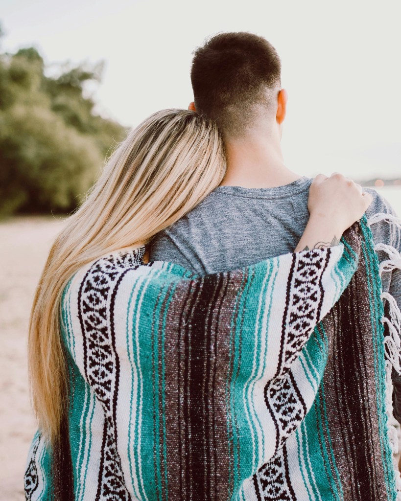 A woman putting her arms around a man. 