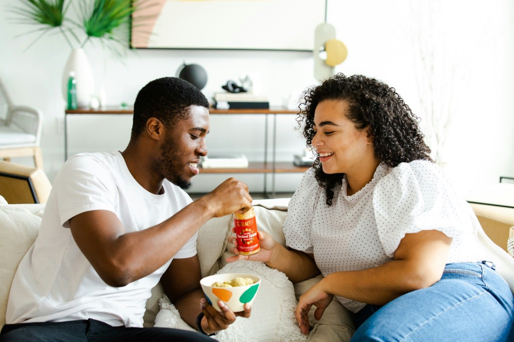 A couple sharing a snack together on the couch. 